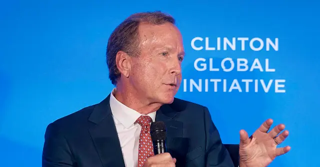 A man in a suit and tie is speaking at the Clinton Global Initiative, gesturing with his hands as he addresses the audience.