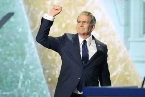 A man in a suit raises his fist in a gesture of triumph or solidarity on stage.