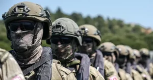 A group of soldiers in tactical gear and helmets stand in formation, ready for deployment.