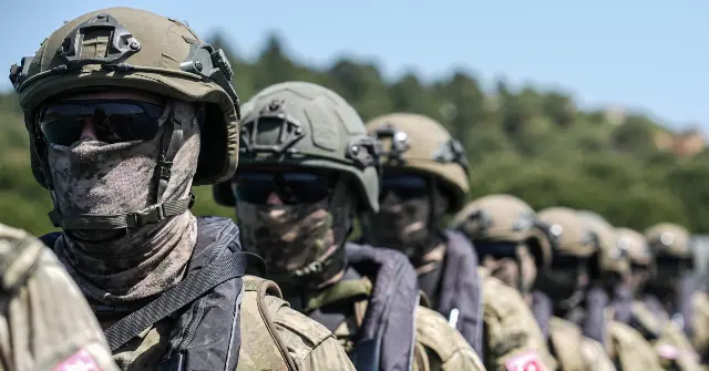 A group of soldiers in tactical gear and helmets stand in formation, ready for deployment.