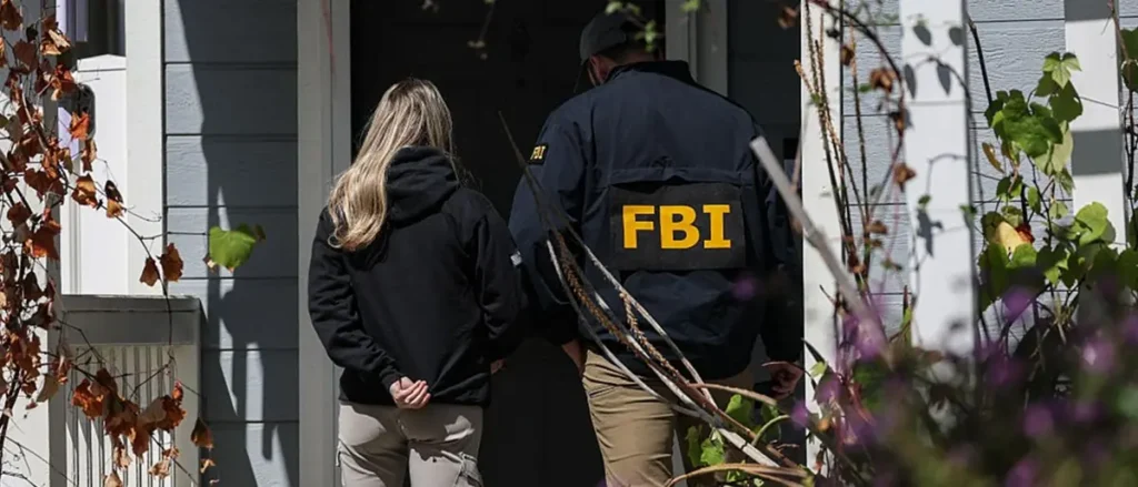 An FBI agent and a person in a black jacket are seen entering a house.