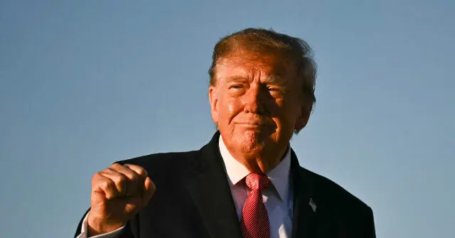 The image shows a person in a suit and tie, standing outdoors with a fist raised, set against a clear blue sky.