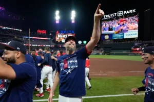 A baseball player celebrates with his teammates on the field after a game, pointing towards the crowd.