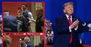 The image shows a political rally with a man in a suit and tie clapping, while in the inset, security personnel are seen restraining a person who appears to be shouting.