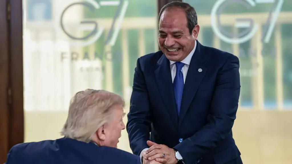 The photo shows two individuals shaking hands in front of a backdrop featuring the "G7 France" logo.
