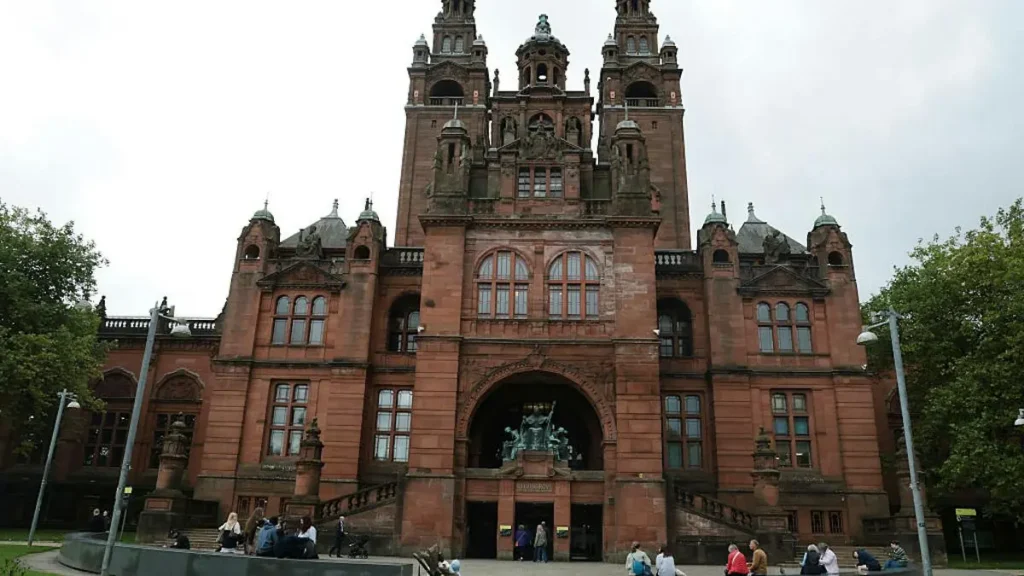 The image shows the Kelvingrove Art Gallery and Museum in Glasgow, Scotland, a grand red-brick building with ornate architectural details and a prominent central entrance.
