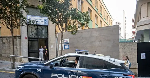 A police car is parked outside a building labeled "Colegio San Juan Bautista," with two individuals standing near the entrance.