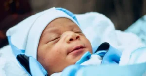 A newborn baby is peacefully sleeping, wrapped in a blue blanket.