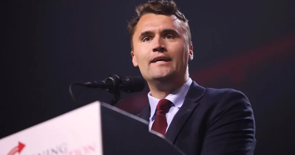 A man in a suit and tie is speaking at a podium during a formal event.