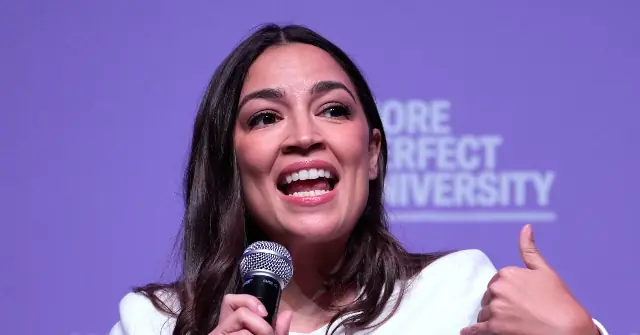 A woman is giving a speech or presentation, holding a microphone and giving a thumbs-up gesture, with a purple background that includes the text "MORE PERFECT UNIVERSITY."