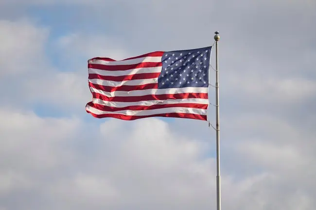 The American flag waves proudly against a backdrop of a cloudy sky.