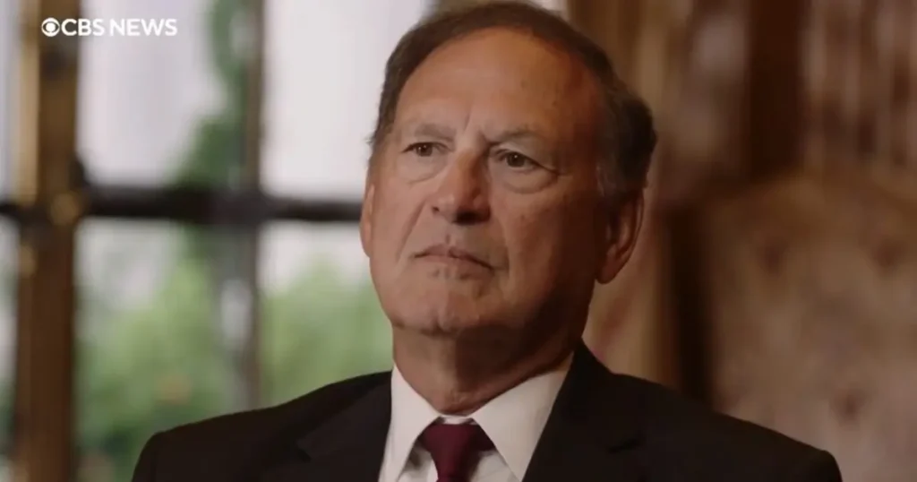 The image shows a man in a suit and tie, appearing in a CBS News broadcast.
