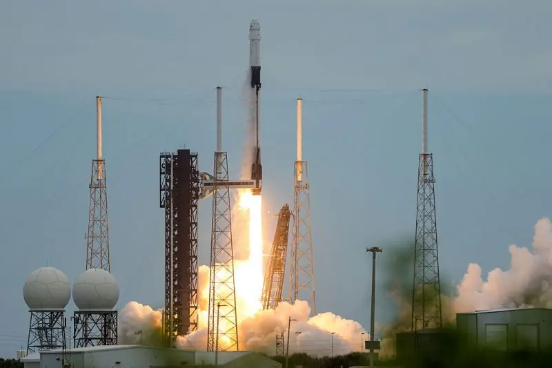 A rocket lifts off from a launchpad, surrounded by smoke and flames, as part of a space mission.