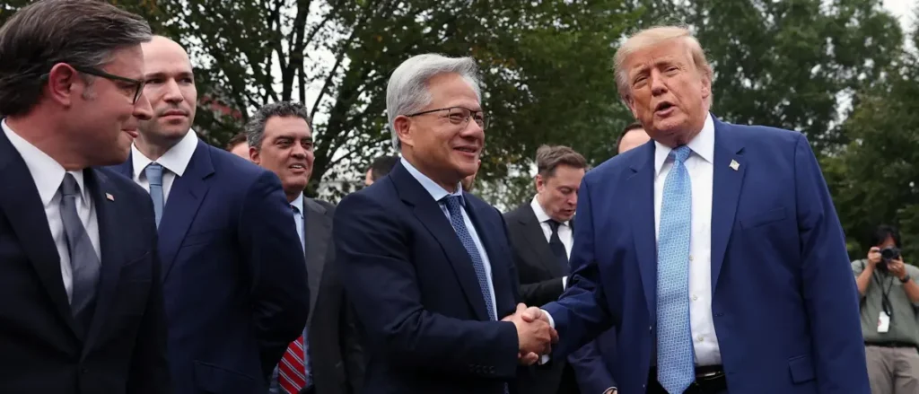 The photo shows a group of men in suits shaking hands outdoors, with one man in a blue suit and tie appearing to be the focus of the interaction.