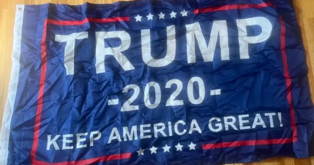 The image shows a campaign flag for a political candidate, featuring the text "TRUMP 2020 KEEP AMERICA GREAT!" with a patriotic design.