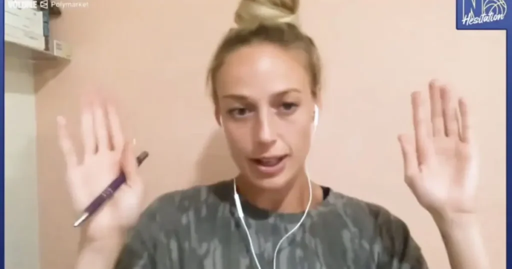 A person is holding a pen and gesturing with their hands while wearing earphones.
