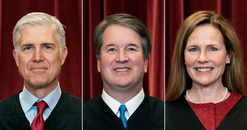 The image shows three individuals in judicial attire, likely representing Supreme Court justices, against a red curtain backdrop.