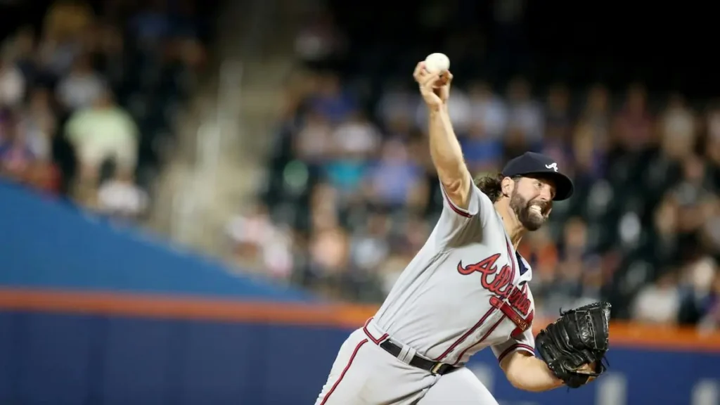 A baseball pitcher in a gray uniform with "Atlanta" written on the jersey is in the middle of a pitch during a game.