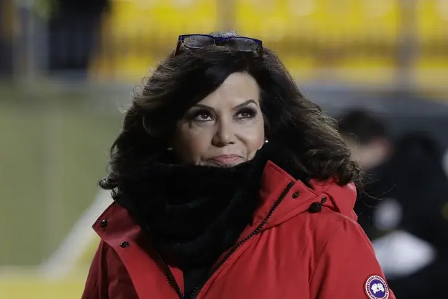 The image shows a person wearing a red Canada Goose jacket and a black scarf, standing outdoors in a cold environment.