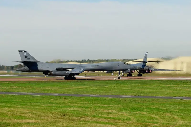 A military aircraft is taxiing on a runway at an airfield.