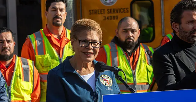 A woman speaks at a podium in front of a group of street service workers.