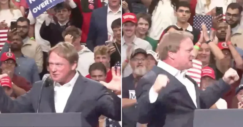The image shows a man at a podium addressing a crowd, with one hand raised and the other clenched in a fist, suggesting a moment of emphasis or passion during his speech.
