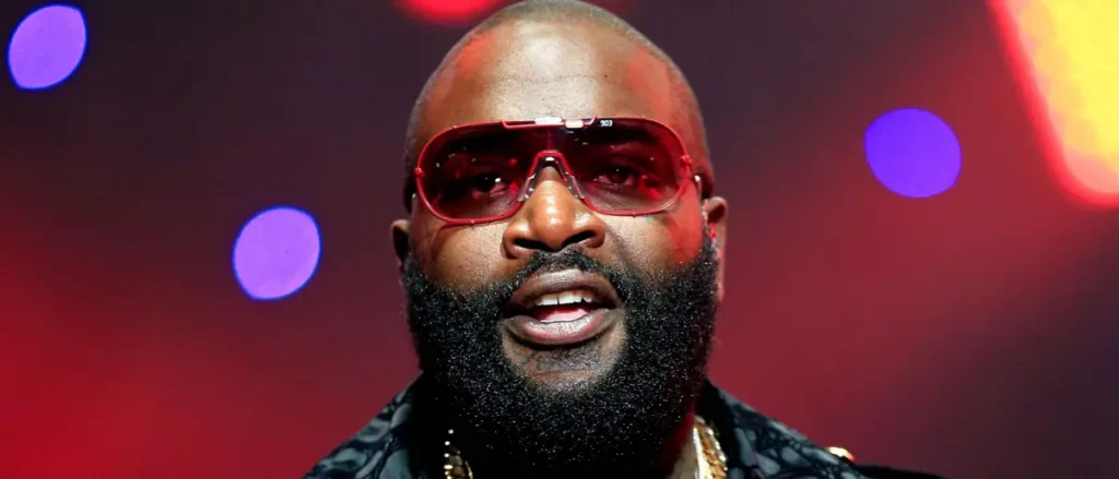 The image shows a person wearing red sunglasses and a patterned shirt, set against a vibrant, colorful background with bokeh lights.
