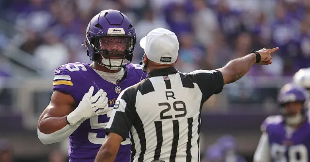 A Minnesota Vikings player gestures while standing next to an NFL referee during a game.