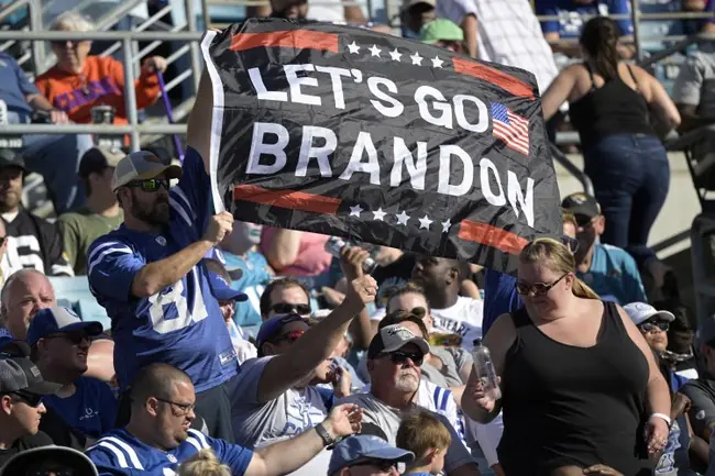 A fan holds up a sign reading "LET'S GO BRANDON" at a sporting event.