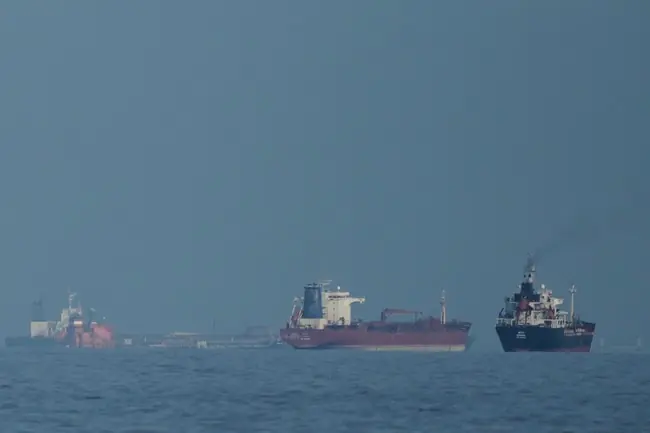 The image shows a group of ships sailing on calm waters under a clear sky.