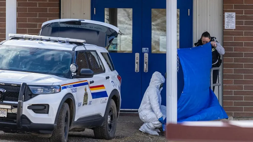 A police officer and a forensic investigator are at the scene of an incident outside a building, with a police vehicle parked nearby.