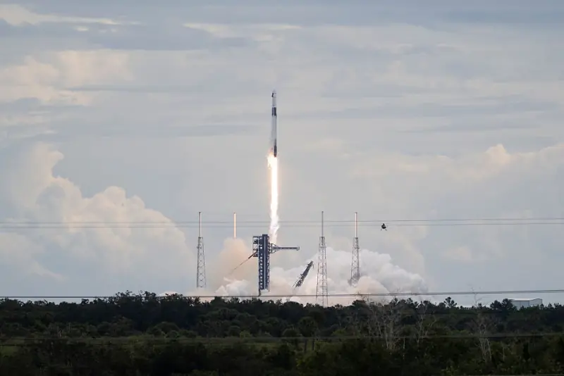 A rocket lifts off from a launchpad, leaving a trail of smoke and fire as it ascends into the sky.