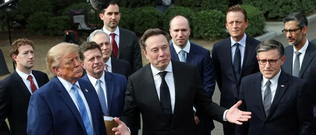 The image shows a group of men in suits, with one man gesturing while others listen attentively.