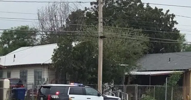 A police car is parked in front of a residential area with houses and trees, suggesting a possible investigation or incident.