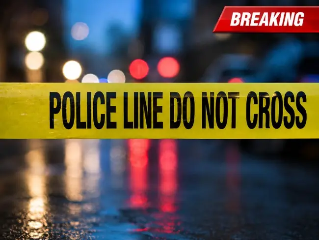 The image shows a "POLICE LINE DO NOT CROSS" tape at a crime scene with blurred lights in the background.
