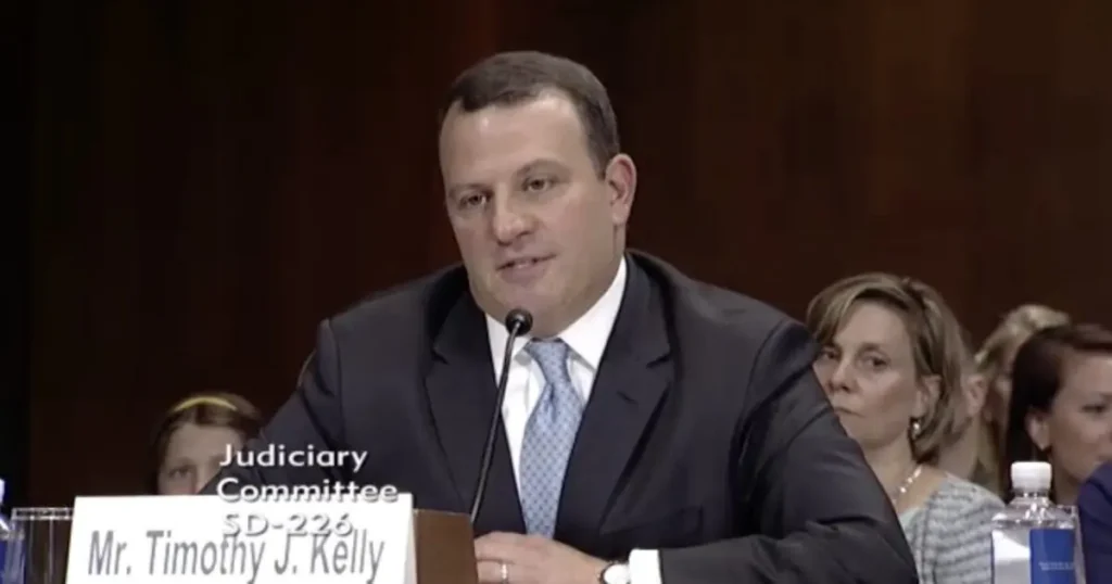 The image shows a man speaking at a Judiciary Committee hearing, with a nameplate identifying him as Mr. Timothy J. Kelly.