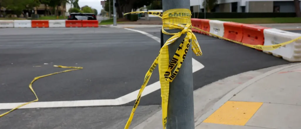 A yellow caution tape is wrapped around a pole at a construction site, indicating a restricted or hazardous area.