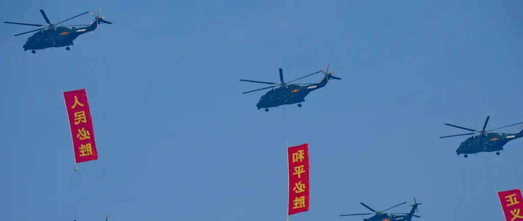 A formation of helicopters flies in the sky, each carrying a red banner with Chinese characters.