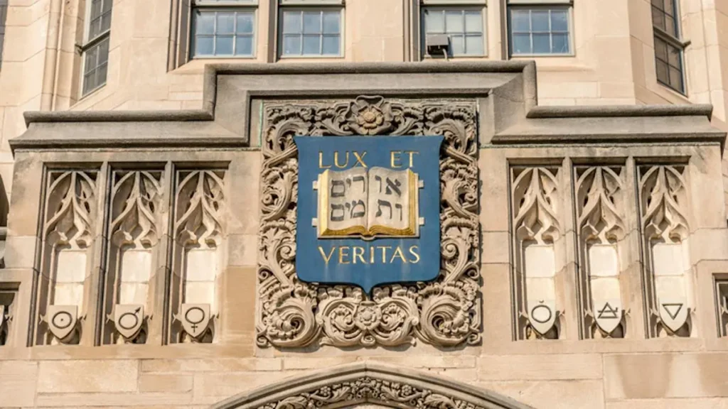 The image shows a decorative stone facade with the Latin phrase "LUX ET VERITAS" and Hebrew script, symbolizing light and truth, likely representing a university or institution.