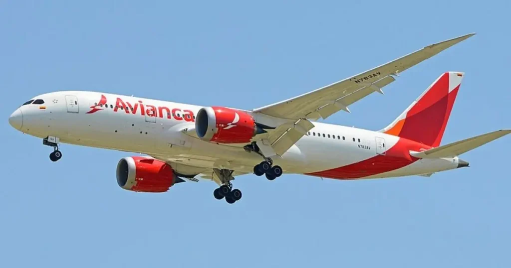 An Avianca Boeing 787 aircraft is captured in flight against a clear blue sky.