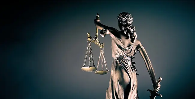 The image depicts a statue symbolizing justice, holding a sword and scales, representing the balance of law and power.