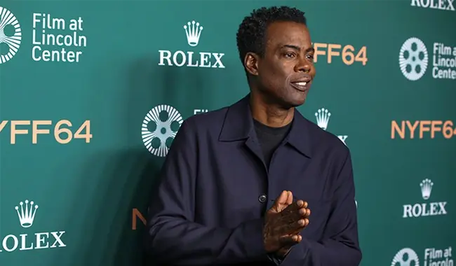 The image shows a person at the New York Film Festival (NYFF64), standing in front of a backdrop featuring logos for Rolex and Film at Lincoln Center.