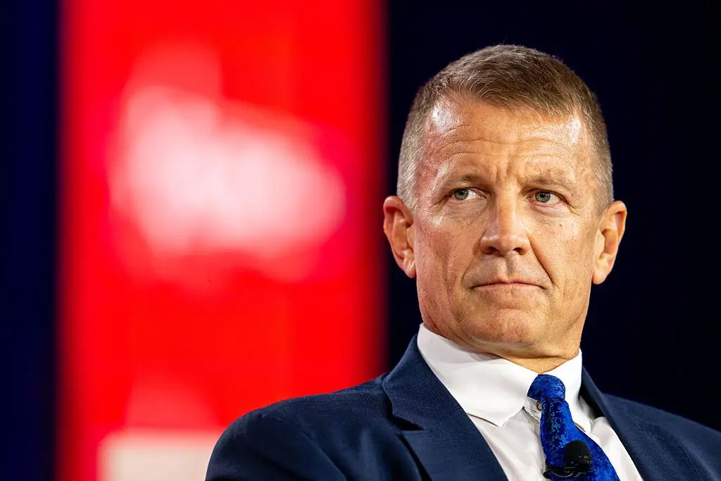 The image shows a man in a suit and tie, appearing to be in a professional or formal setting, possibly during a news interview or press conference.